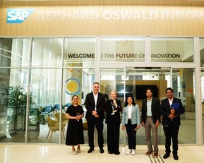 Sechs Personen stehen vor dem Eingang zum Gerhard Oswald Innovationszentrum von SAP, mit einem Banner, das "WELCOME TO THE FUTURE OF INNOVATION" zeigt.